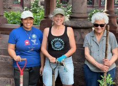 Three women smile after working in the St. Francis Garden on a sunny spring day