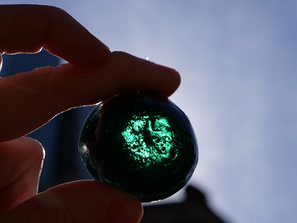 The nuggets of stained glass are mostly round and polished, with one flat side.